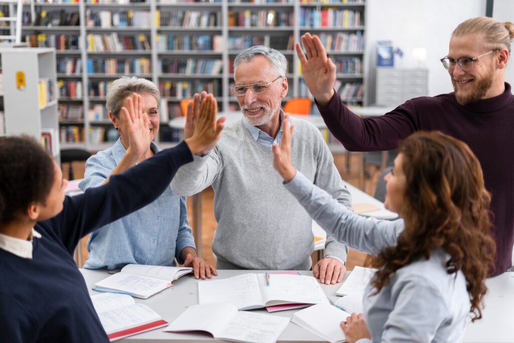 Personnes de différents âges se félicitant avec un high five autour d’une table.